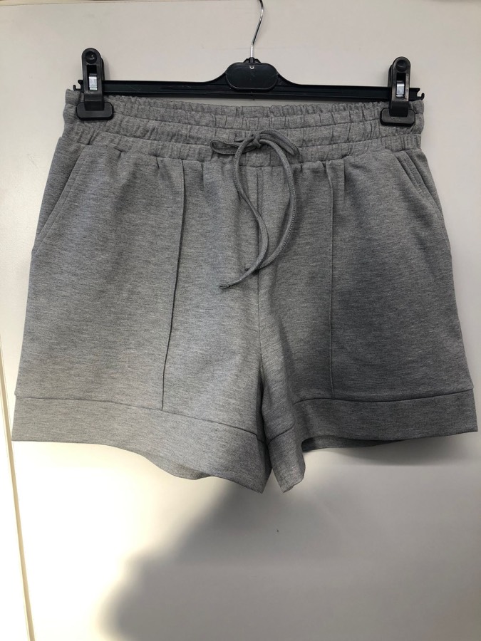 Grey shorts photographed with harsh shadows across the background