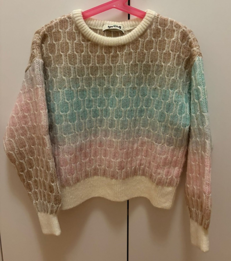 Knitted jumper on a plastic hanger photographed from an angle